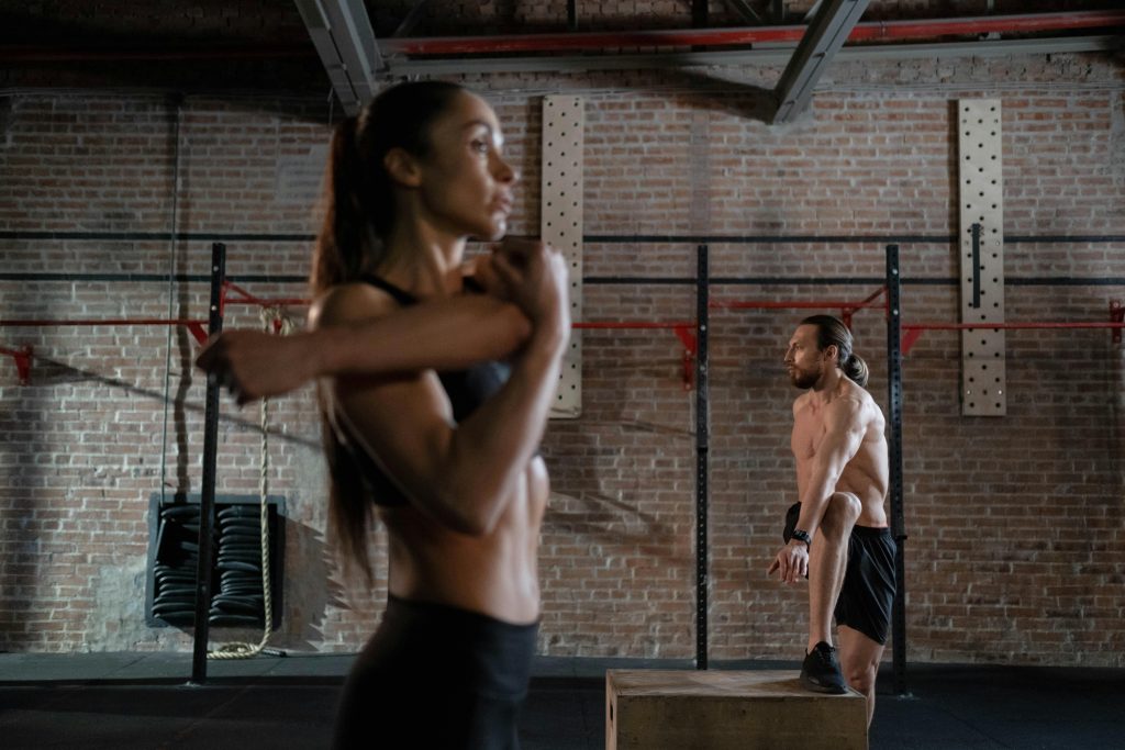 Two athletes warming up in an industrial-style gym, preparing for an intense workout session.